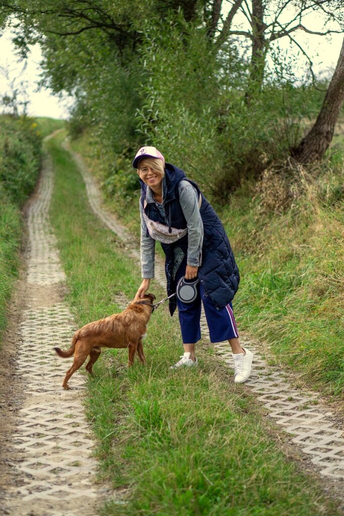 kobieta wypowadzająca psa na polnej drodze